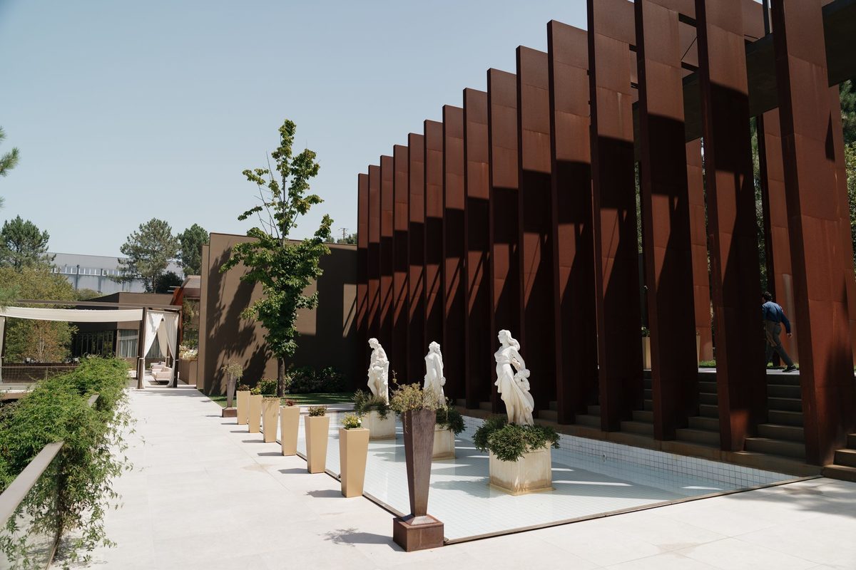 Pátio com estátuas clássicas, espelho de água e lâminas em aço corten