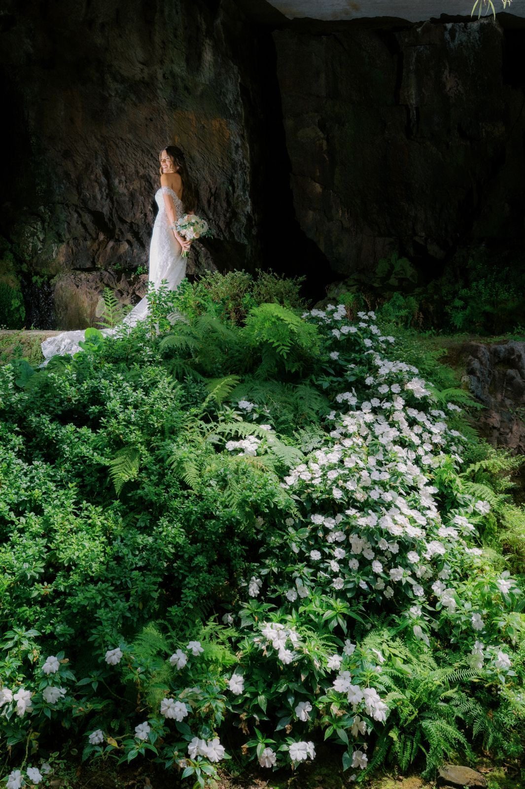 Noiva entre hortênsias e vegetação junto a uma parede de pedra