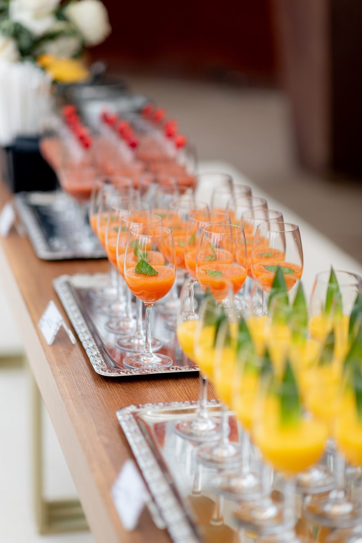 Copos de sumos e cocktails coloridos alinhados em mesa de madeira