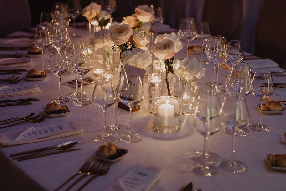 Mesa de jantar com copos de cristal, rosas brancas e velas