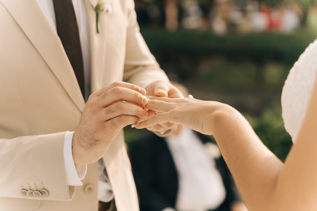 Noivo colocando a aliança na noiva.