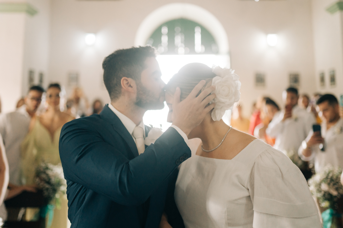 Noivo beijando a testa da noiva no altar.