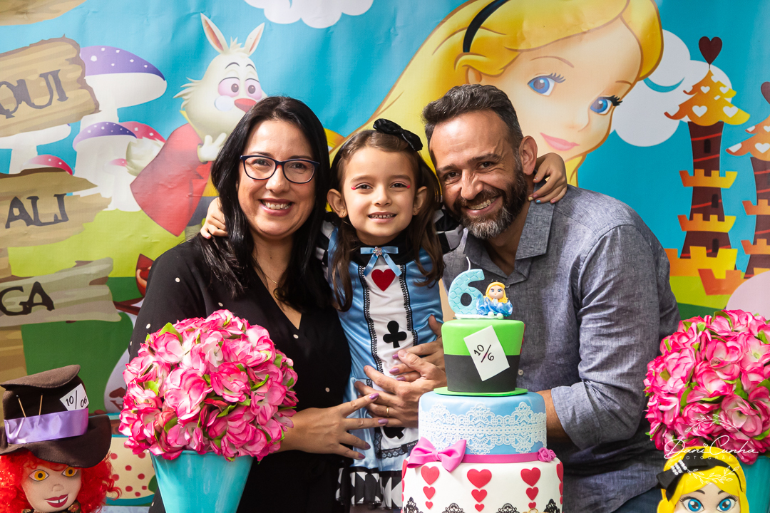pai e mãe abraçando filha em festa Alice no País das Maravilhas