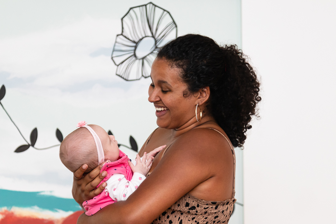mulher negra segurando bebe no colo e sorrindo para ela
