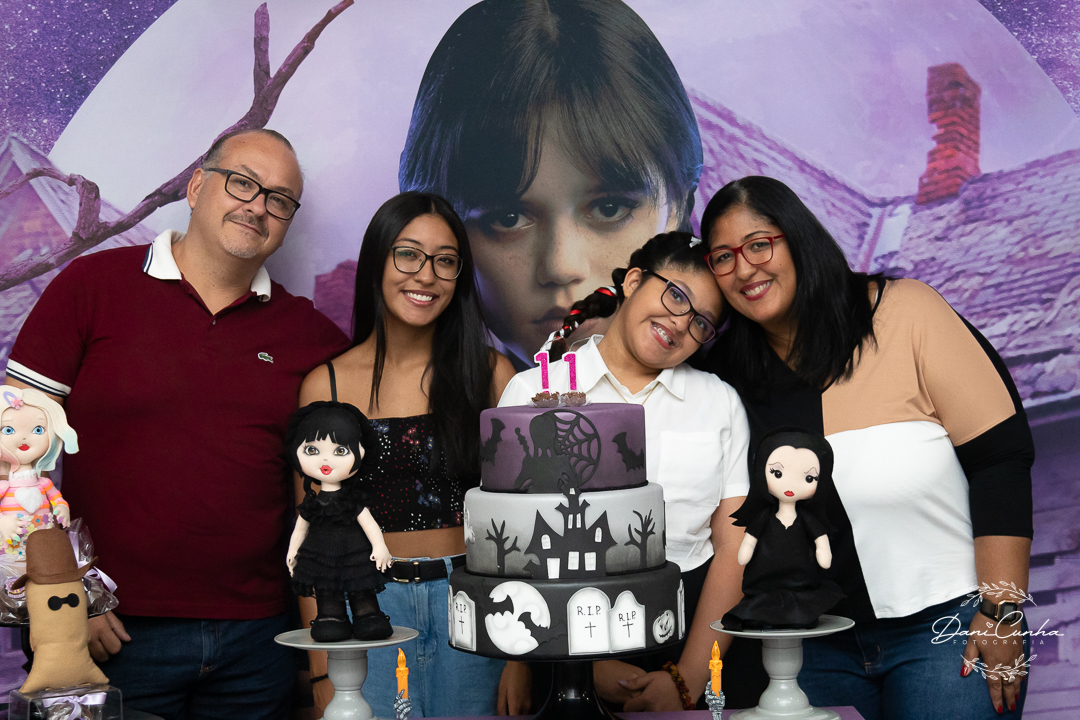 aniversariante abraçada com sua família em mesa decorada com o tema wandinha