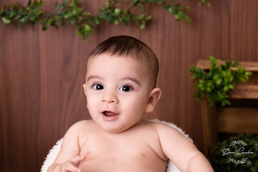 foto de bebe com leve sorriso em fundo de madeira