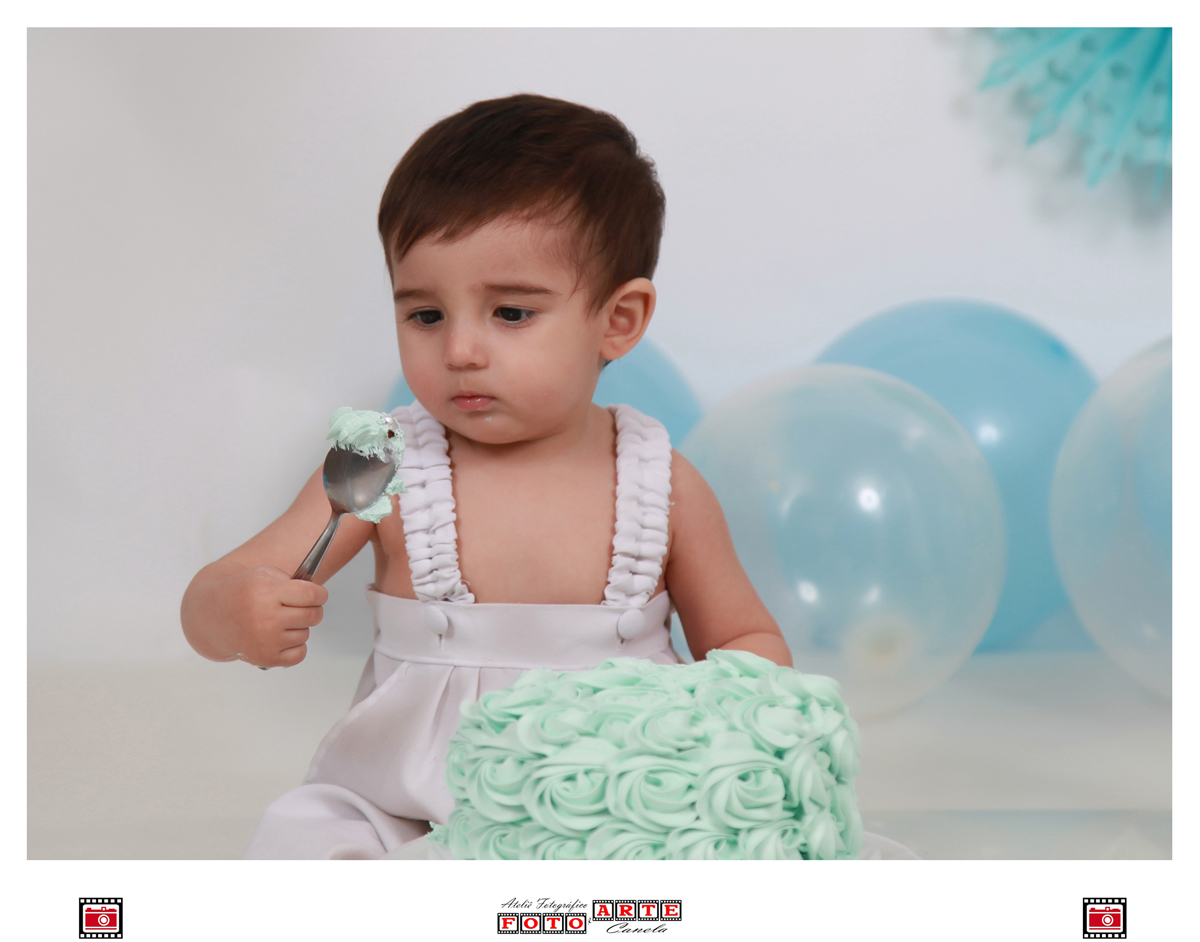 criança olhando para a colher com bolo em seu ensaio smash the cake 