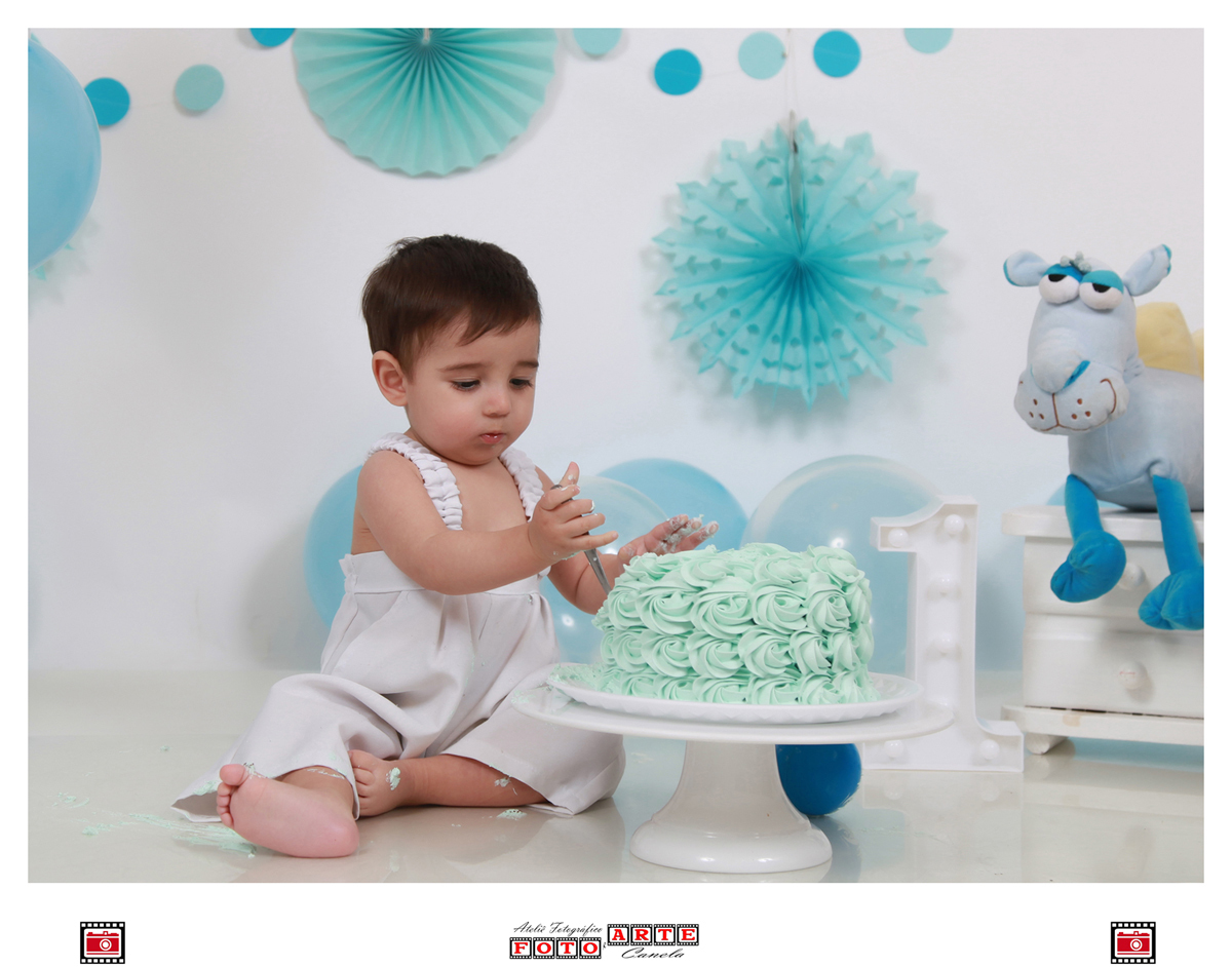 bebê brincando com a colher no bolo em seu ensaio smash the cake