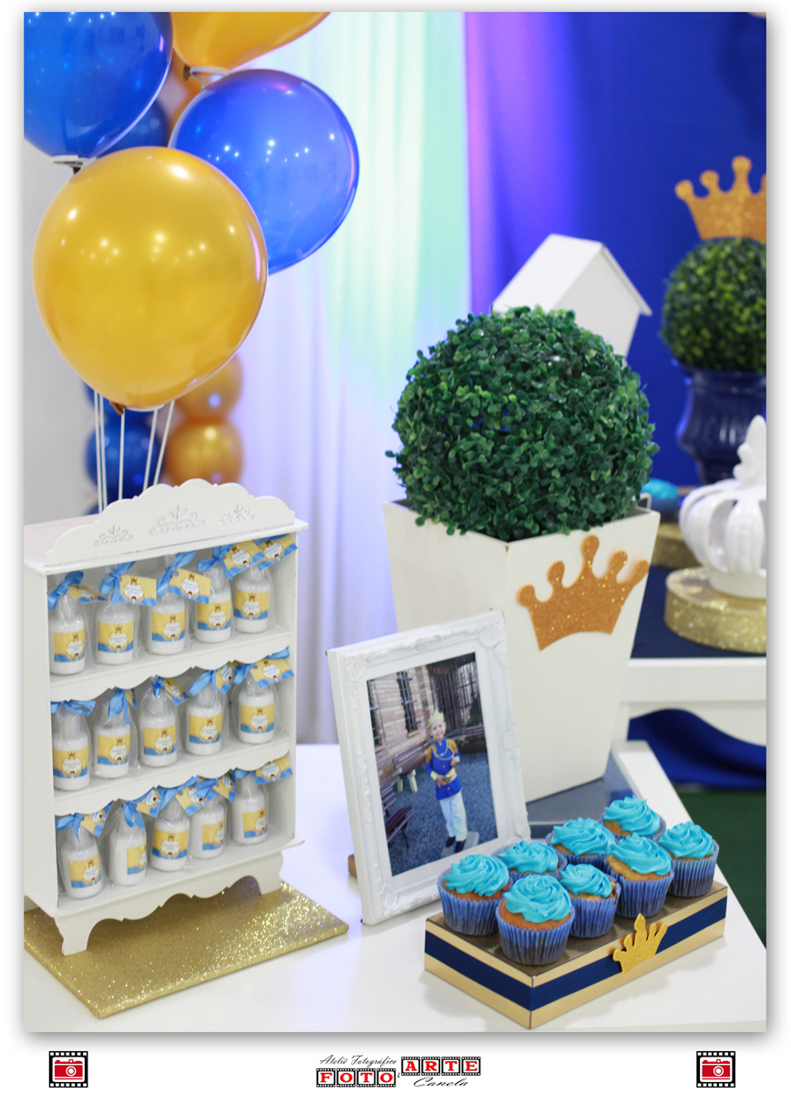 balões dourados e azuis, estante de garrafinhas, quadro com foto e cupcakes azuis