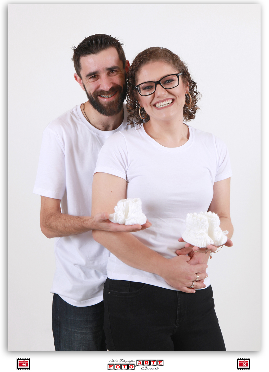 casal de branco segurando sapatinhos de crochê