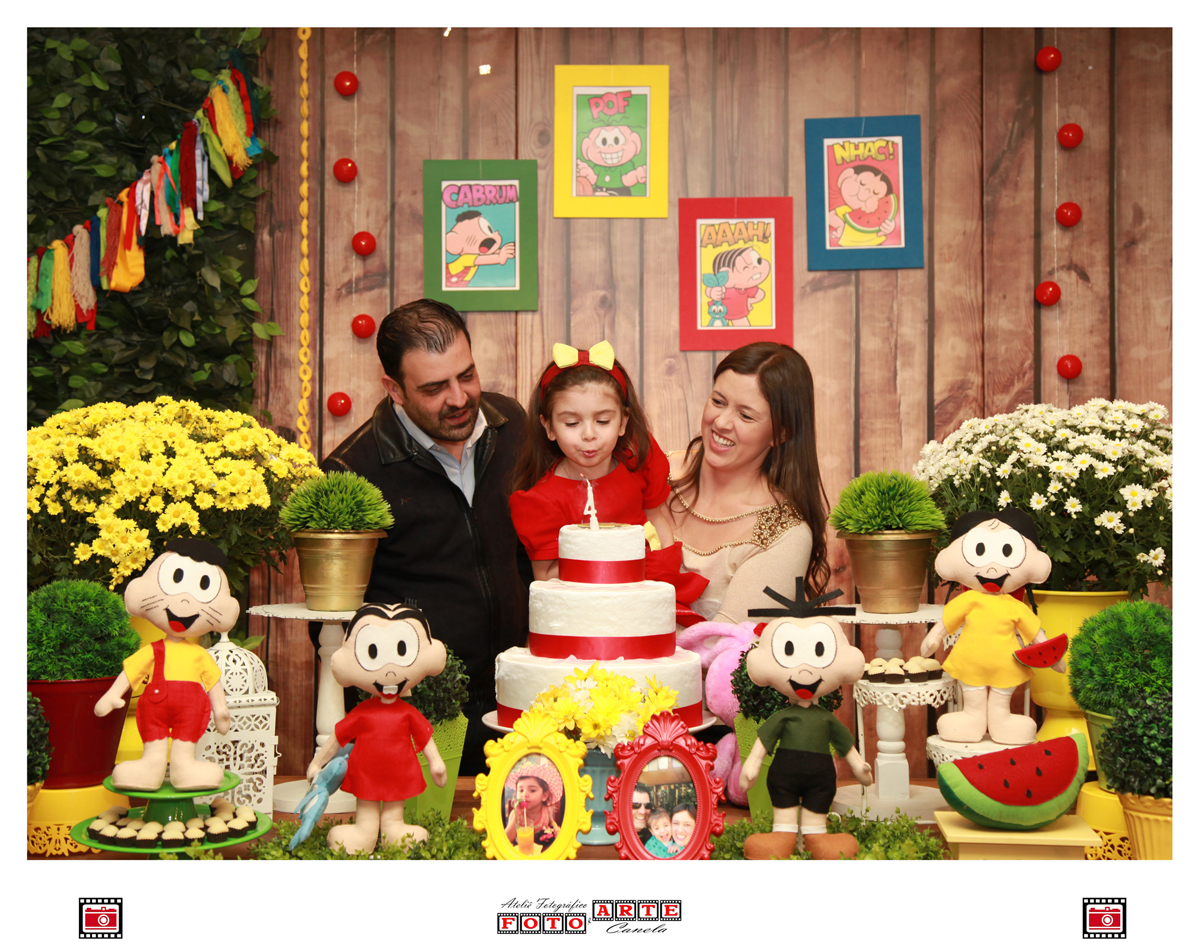 criança assoprando as velinhas com os pais na mesa do parabéns