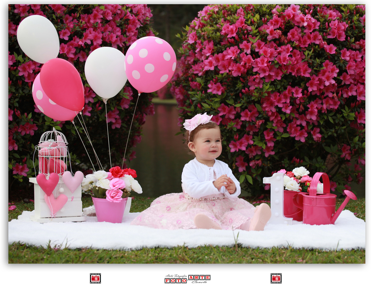 menina sentada no tapete branco com decoração de balões cor de rosa
