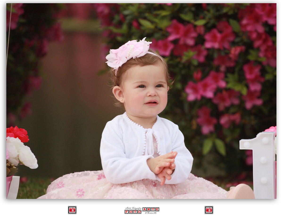 menina sentada com fundo de flores rosas