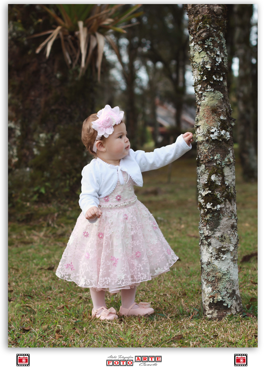 menina de vestido rosa se segurando na árvore
