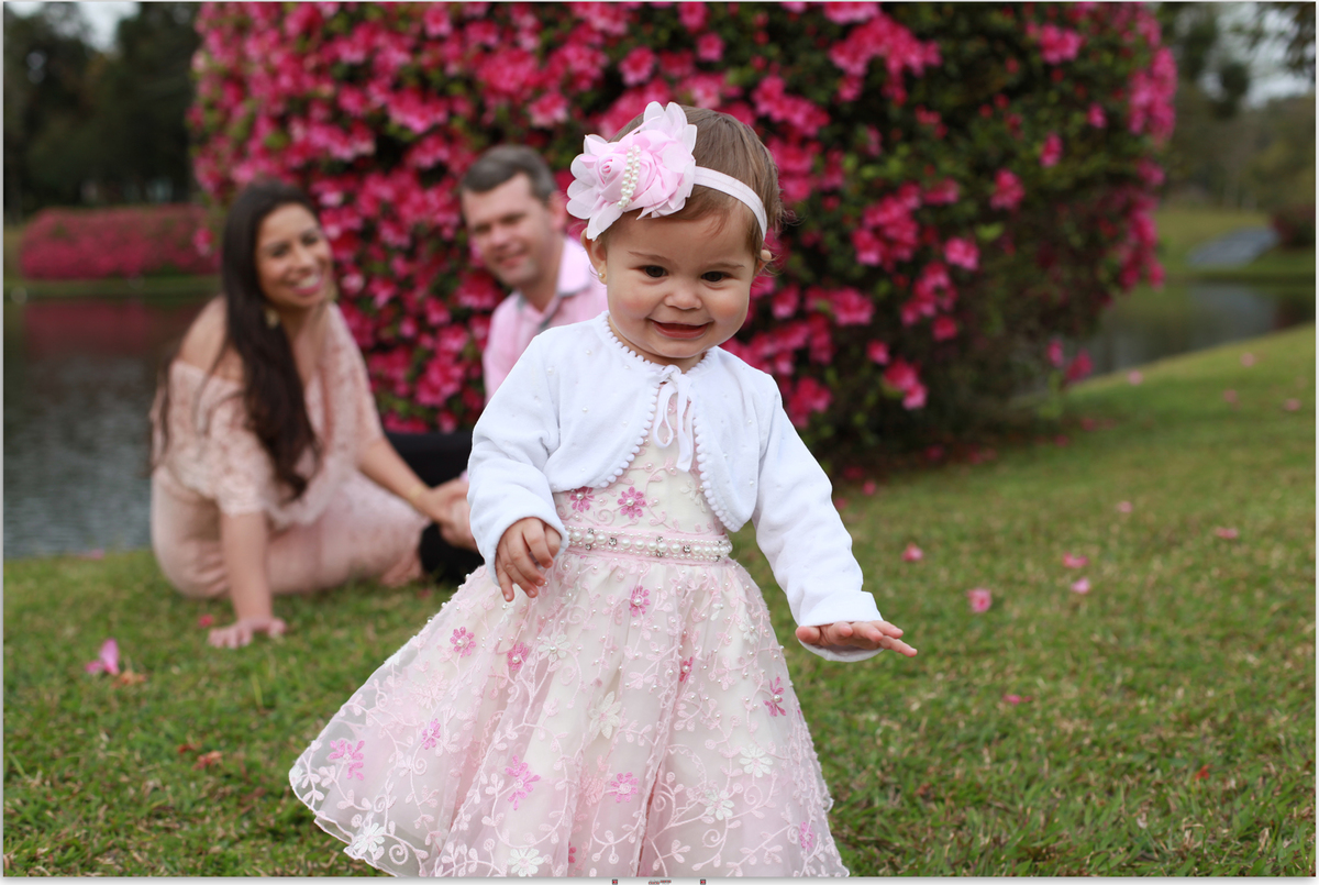 menina sorrindo com os pais ao fundo