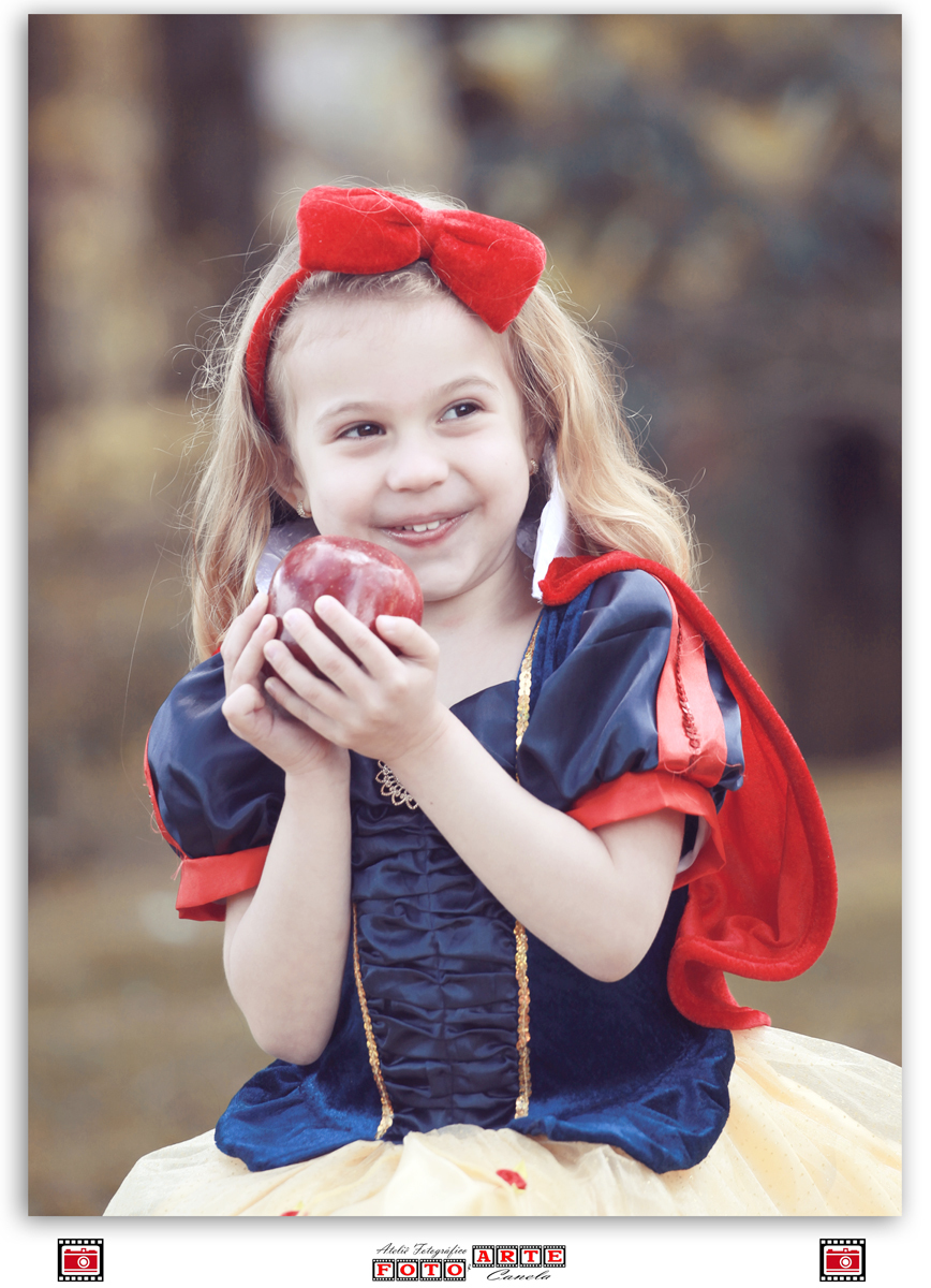 menina segurando maçã perto do rosto com fantasia de branca de neve