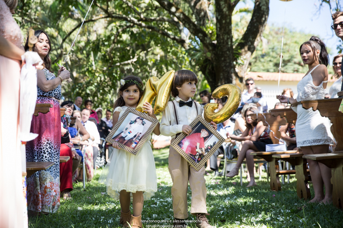 Entrada das crianças levando quadro com fotos dos noivos ainda crianças.