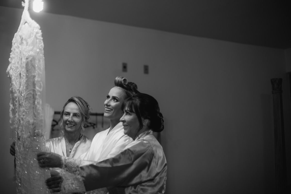 noiva e as mães olhando o vestido da noiva
