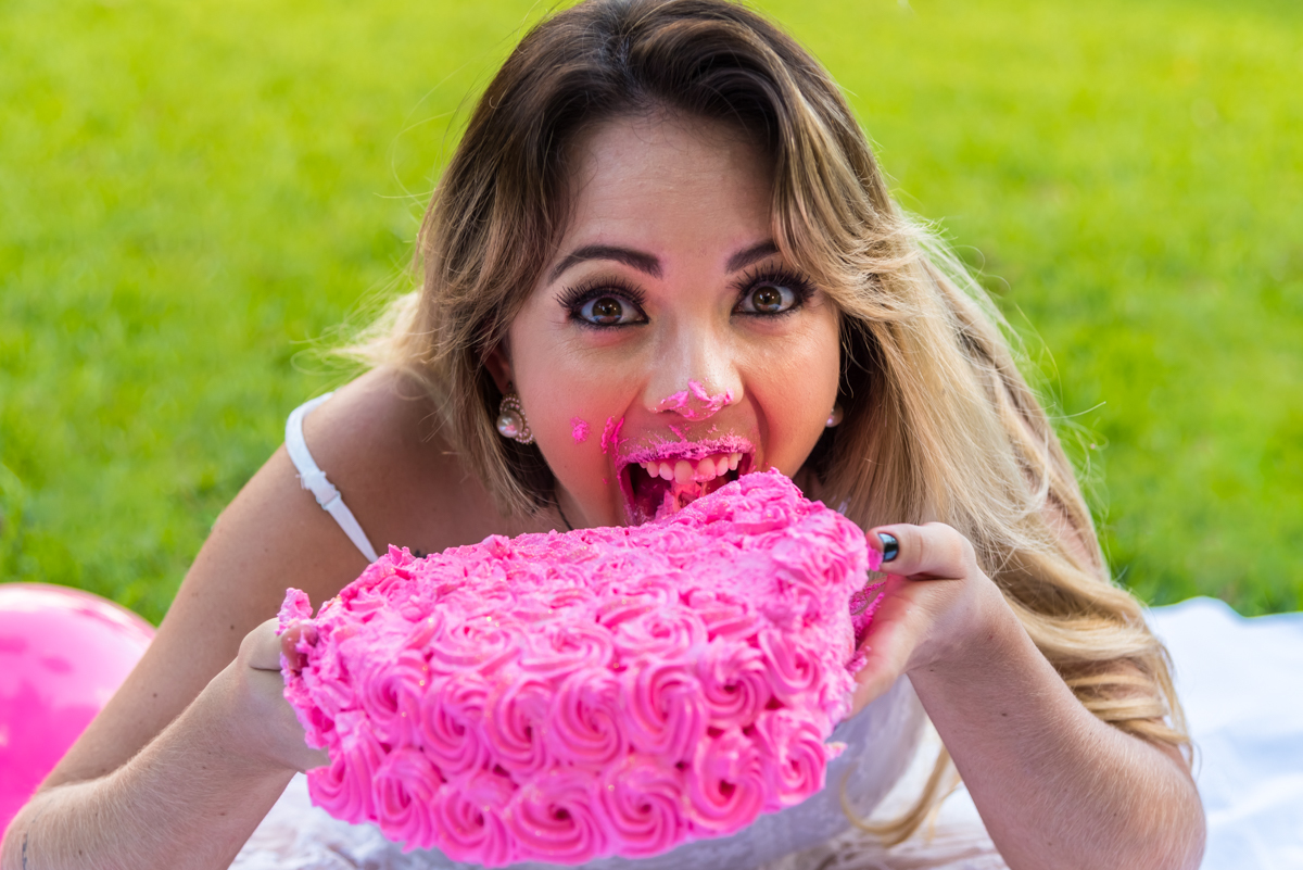 Mayara erguendo o bolo até a boca no seu SMASH THE CAKE EM PANÁPOLIS
