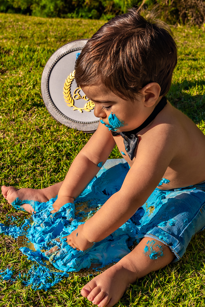 Foto na vertical com o Vicente com as duas mãos no bolo - SMASH THE CAKE EM SÃO PAULO - IBIÚNA