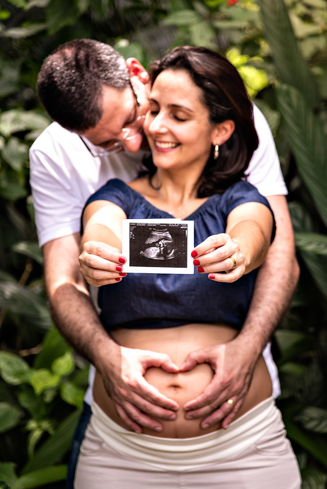 Camila mostrando a radiografia e Marcio fazendo coração na barriga - ENSAIO GESTANTE EM SANTOS - ORQUIDÁRIO DE SANTOS - ENSAIO GESTANTE - FOTOGRAFIA GESTANTE - FOTÓGRAFO DE GESTANTE EM SANTOS - RODRIGO MARTIN FOTOGRAFIA