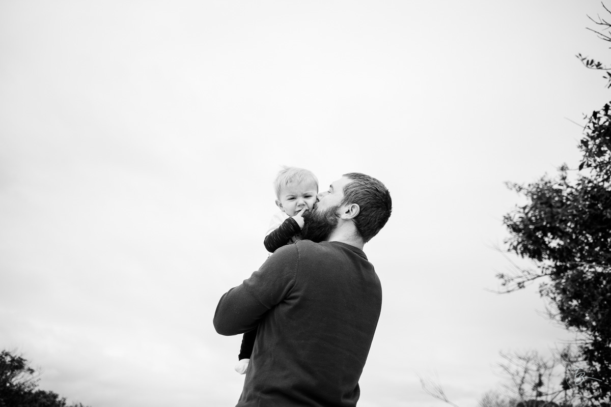 filho abraçado com seu pai durante sessão de fotos. 