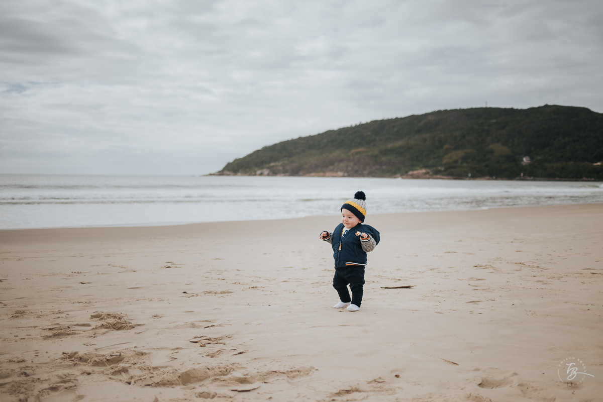 menino na praia, perto do mar, em ensaio de familia