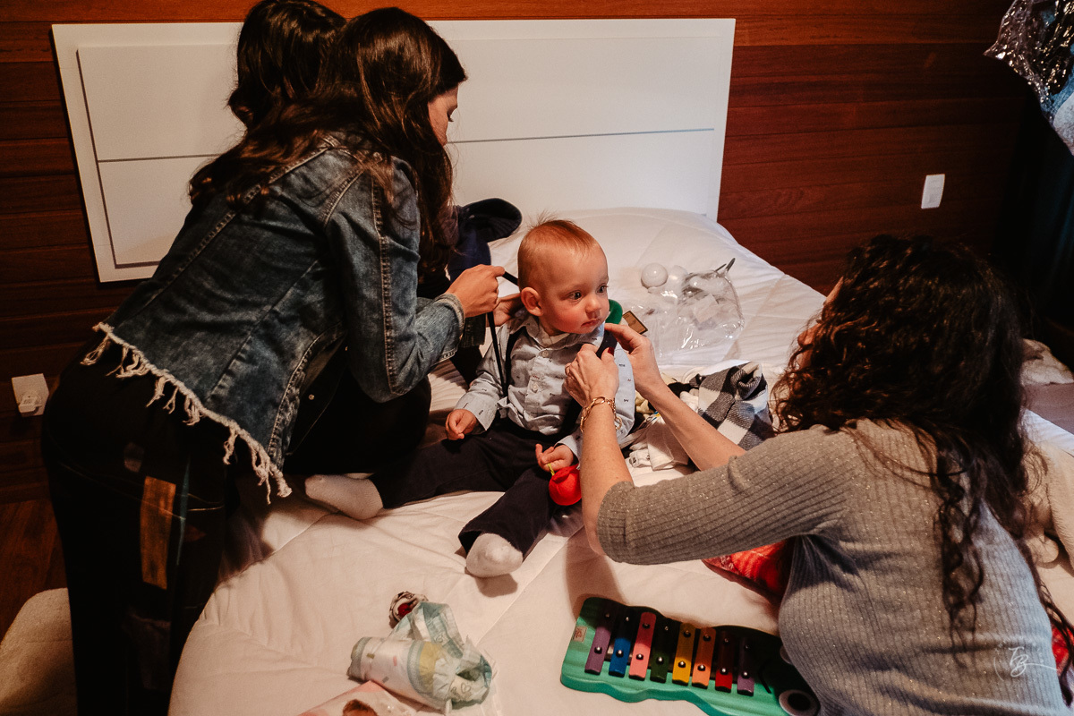Todos arrumando o bebê para sua festa. Fotografia documental de aniversário em Rancho Queimado - SC por Thiago Braga fotografia. Fotografia de aniversário infantil.