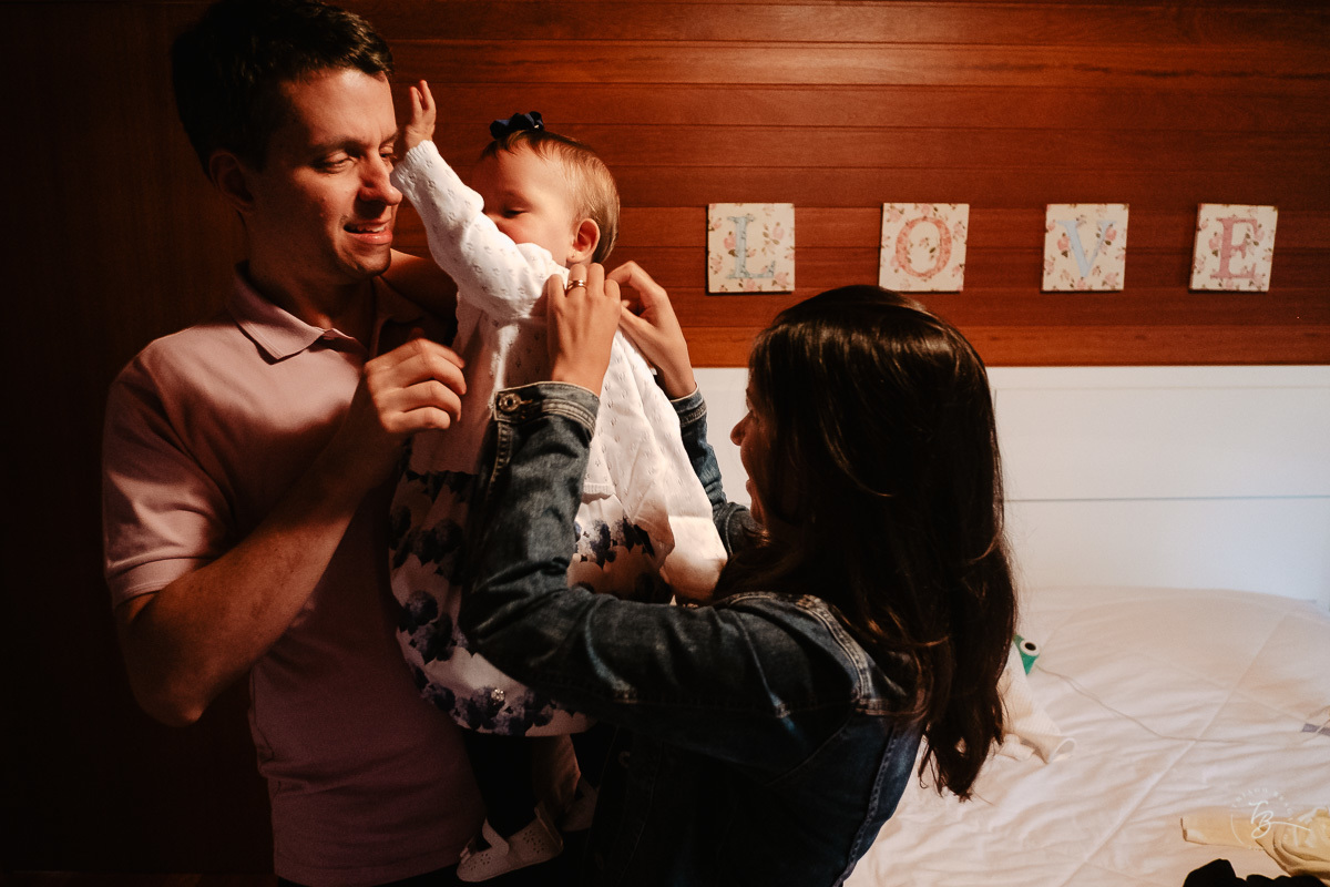 Papai e mamãe arrumando a filha para a festa de aniversário. Fotografia documental de aniversário em Rancho Queimado - SC por Thiago Braga fotografia. Fotografia de aniversário infantil.