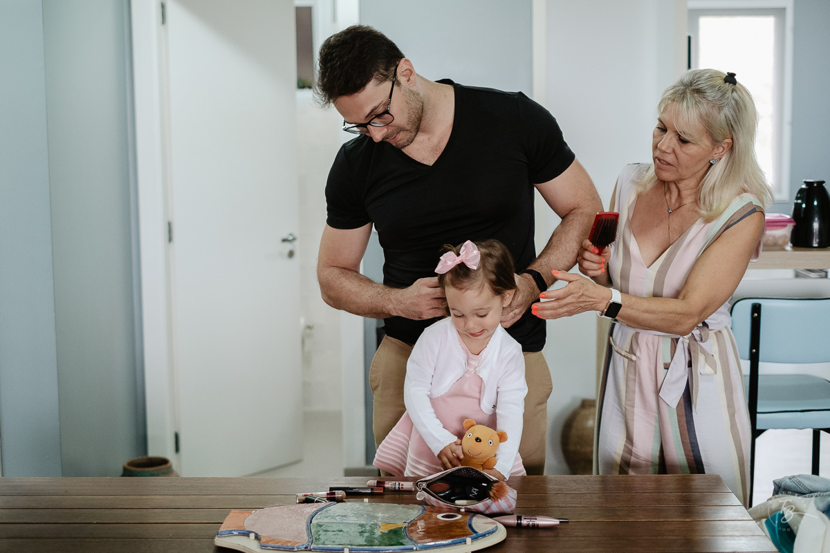 Pai e vó, arrumando sua filha. Fotografia documental de aniversário infantil em Florianópolis/Sc por Thiago Braga.