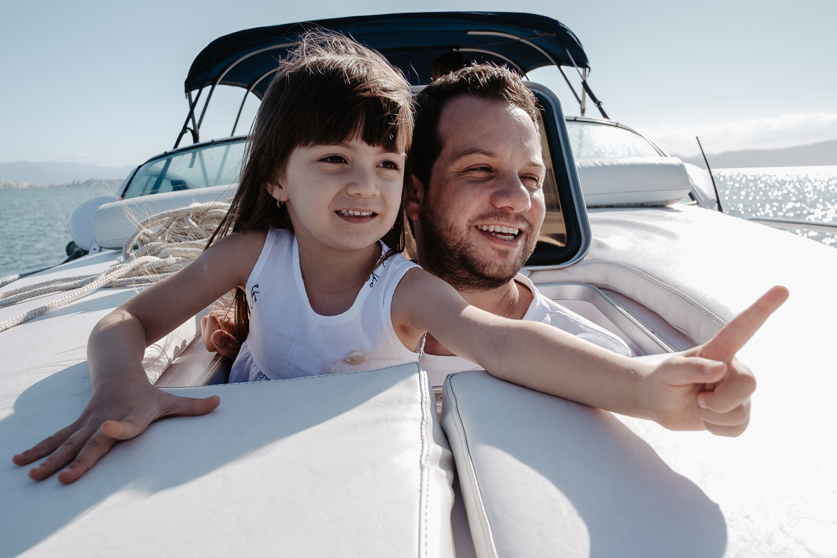 Pai e filha mostrando o mar dentro da cabine. Ensaio gestante em Santo Antônio de Lisboa e Sambaqui, a bordo de uma lancha, na costa oeste de Florianópolis. Por Thiago Braga Fotografia. A espera do Nicolas.