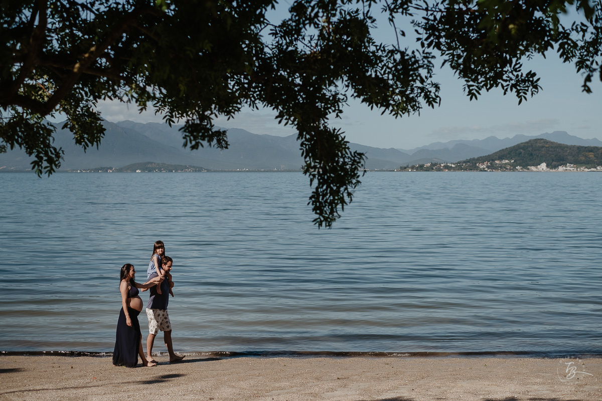 Família caminhando na praia. Ensaio gestante por Thiago Braga Fotografia. Sessão lifestyle na praia do Bom Abrigo, em Florianópolis-SC. 