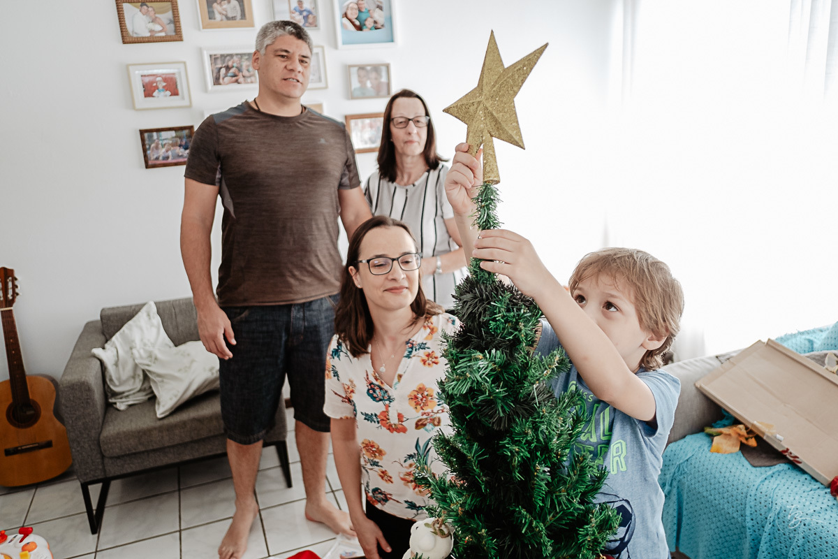 colocando o topo da árvore. Ensaio documental de Natal, em casa, por Thiago Braga fotografia. 