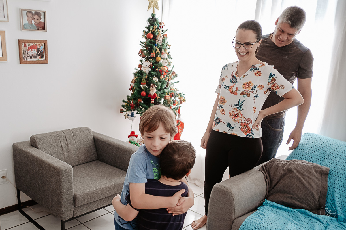 Pais orgulhosos com seus filhos após a montagem da árvore de natal. Ensaio documental de Natal, em casa, por Thiago Braga fotografia. 