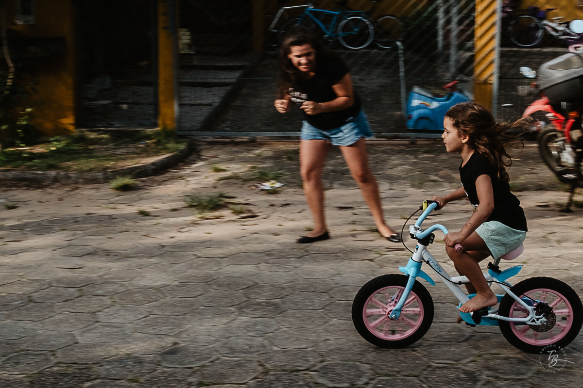 Menina andando de bicicleta na tua. Fotografia documental de família. ensaio de família. Praia do Campeche, por Thiago Braga Fotografia. Família Barcarol.