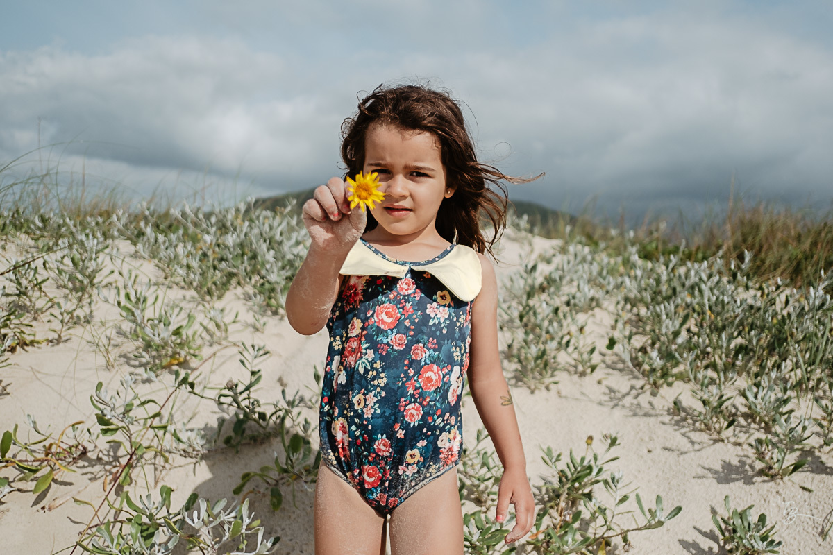 Menina mostrando sua planta Fotografia documental de família. ensaio de família. Praia do Campeche, por Thiago Braga Fotografia. Família Barcarol.