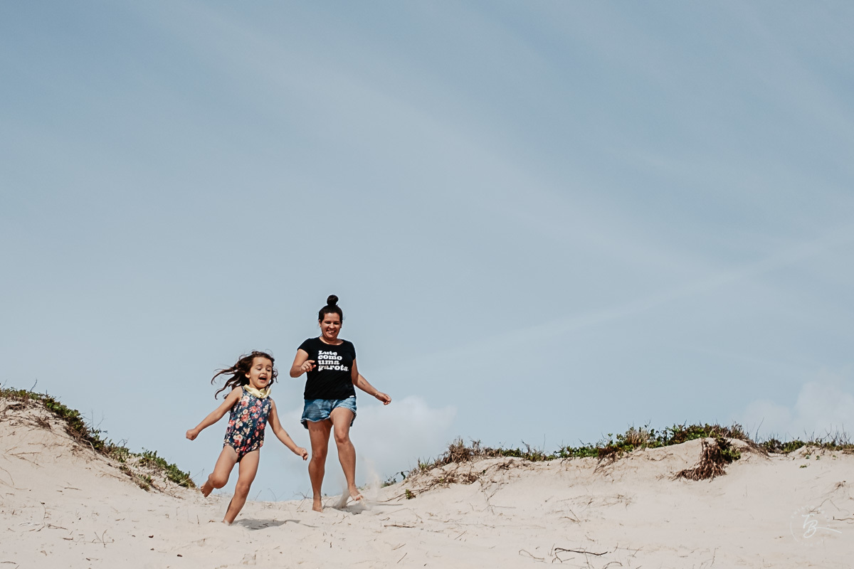 Mãe e filha correndo e se divertindo. Fotografia documental de família. ensaio de família. Praia do Campeche, por Thiago Braga Fotografia. Família Barcarol.