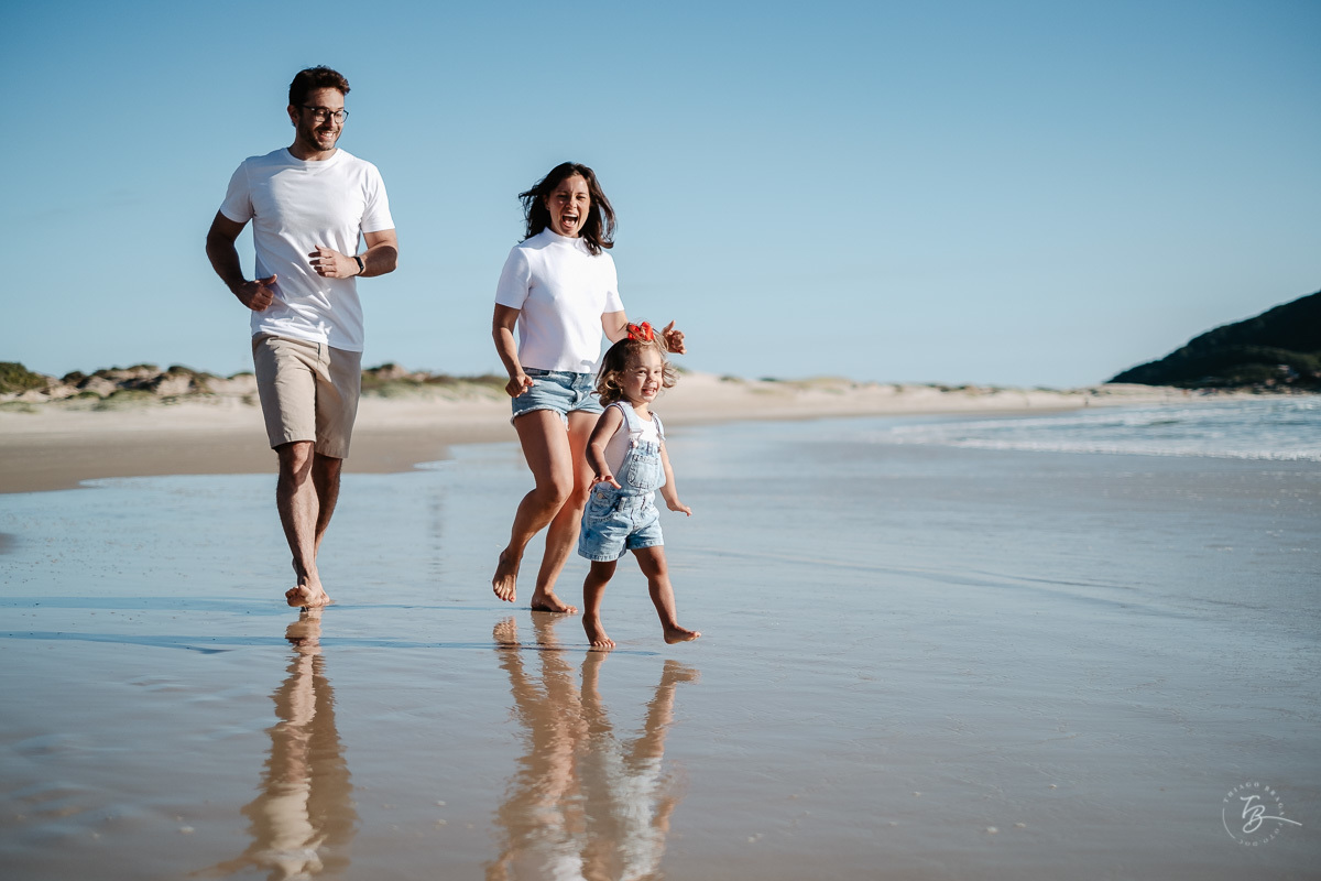 Família correndo e brincando na praia. Ensaio lifestyle família, na praia do Santinho em Florianópolis, por Thiago Braga Fotografia. 