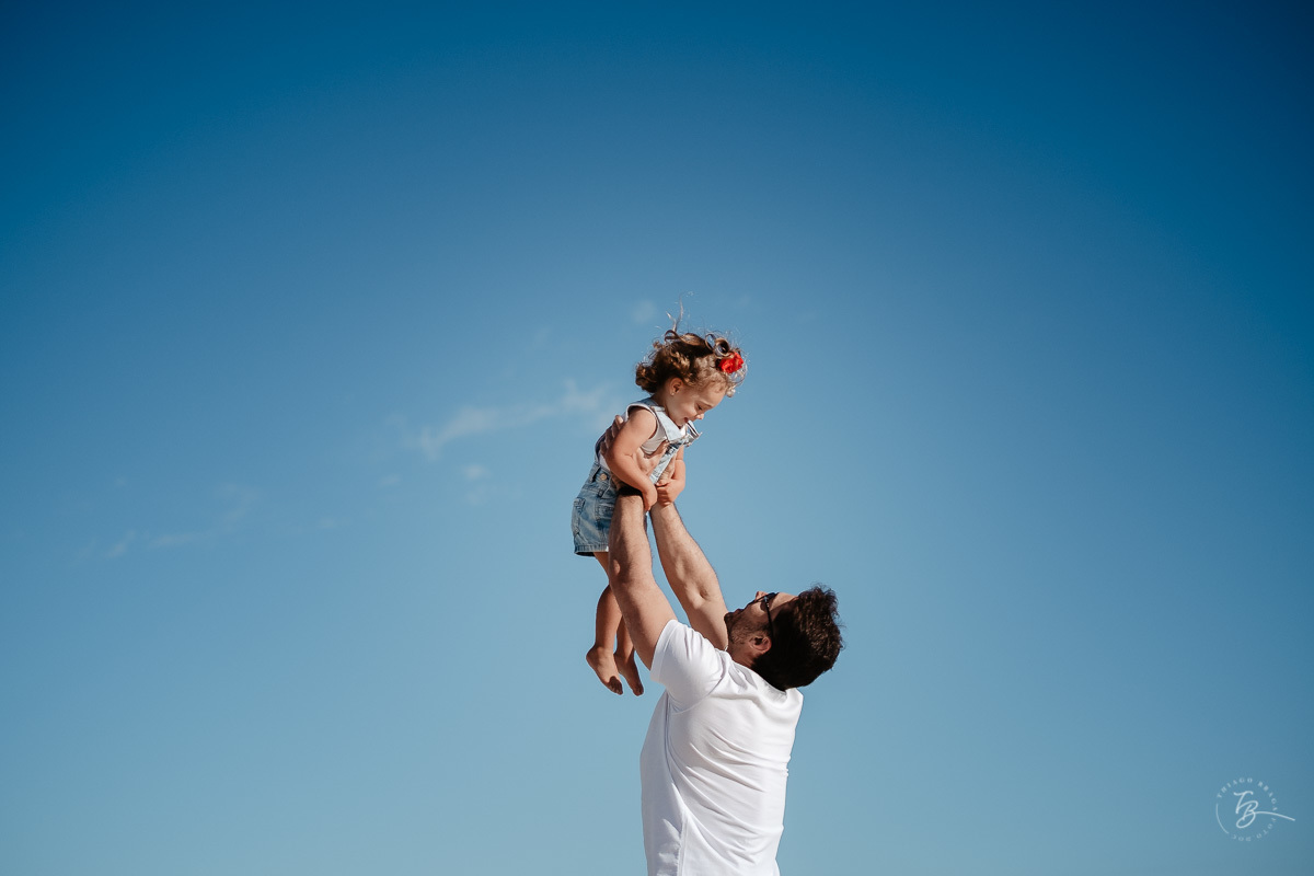 Papai e sua filha. Céu azul. Ensaio lifestyle família, na praia do Santinho em Florianópolis, por Thiago Braga Fotografia. 