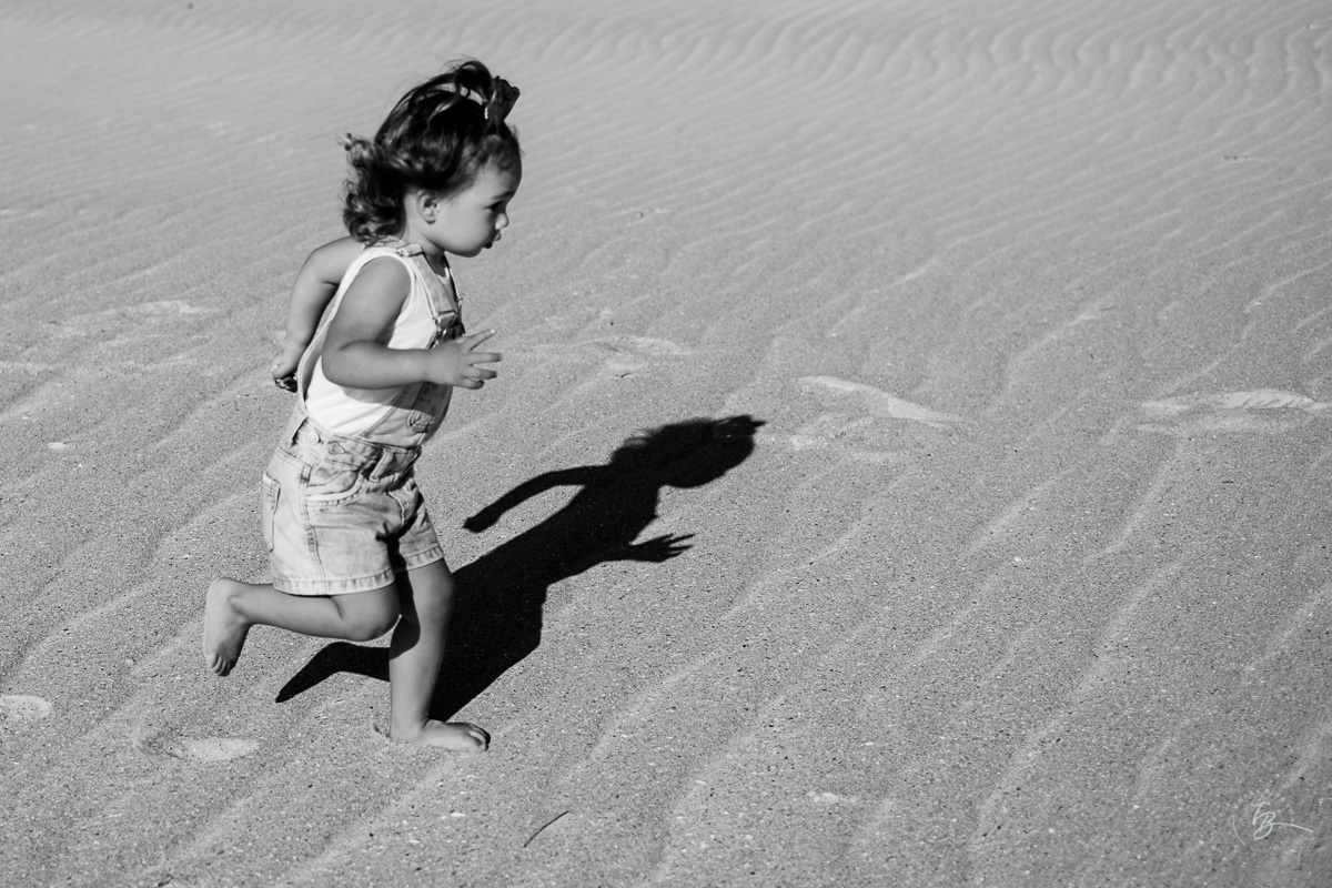 Criança correndo livremente na praia do Santinho. Ensaio lifestyle família, na praia do Santinho em Florianópolis, por Thiago Braga Fotografia. 