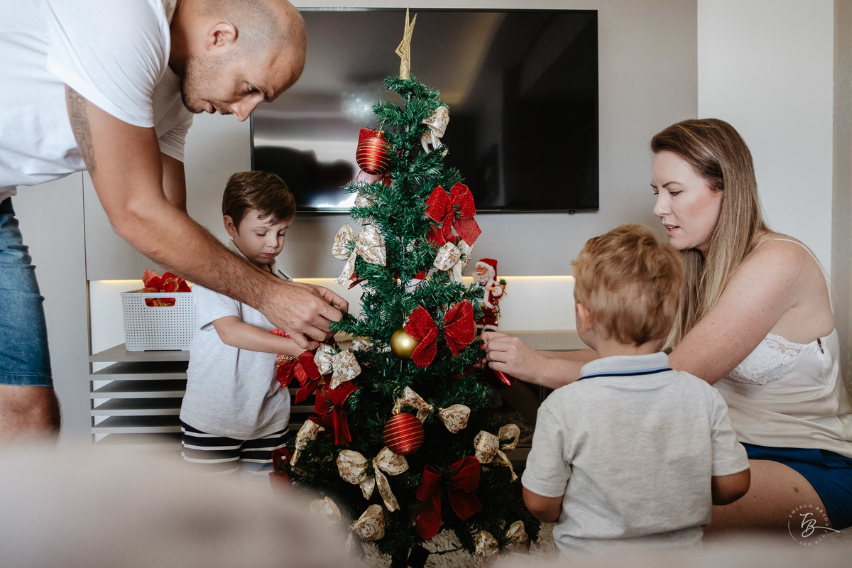 Família arrumando sua árvore de natal. Ensaio de natal em casa por Thiago Braga Fotografia.