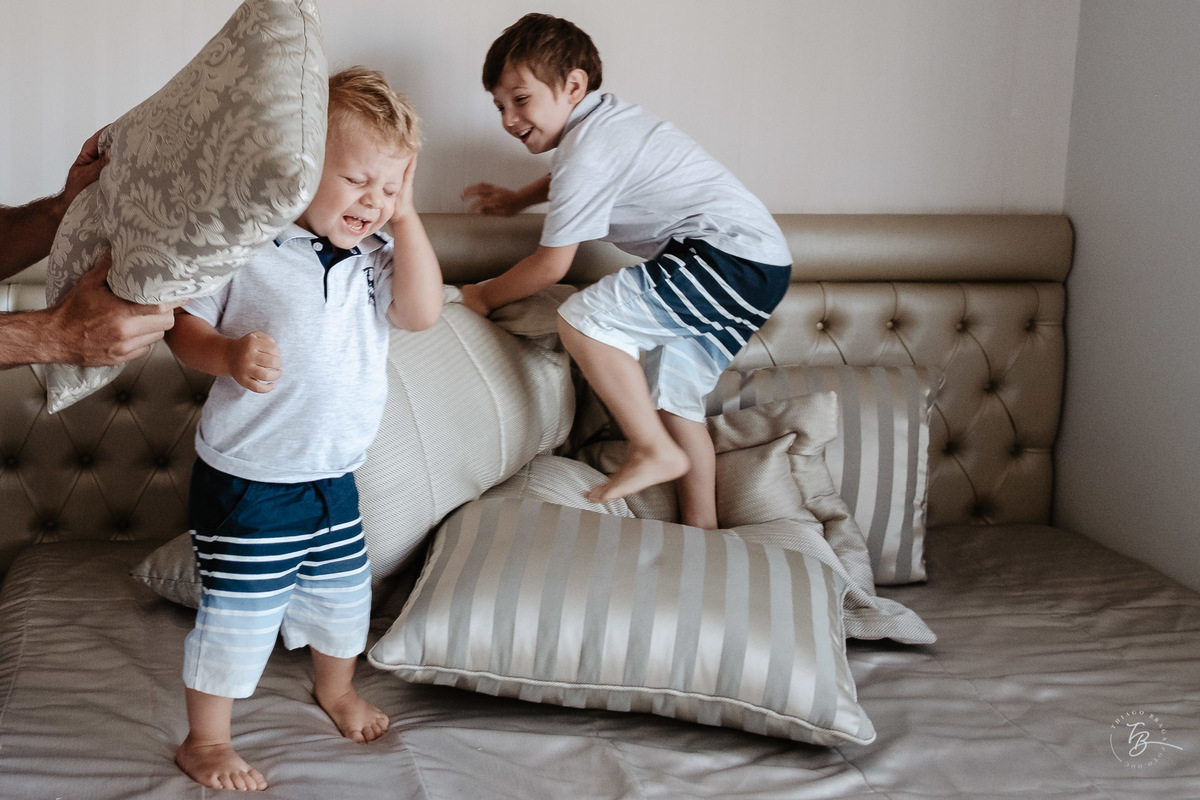 Meninos pulando e fazendo folia na cama dos pais. Ensaio de natal em casa por Thiago Braga Fotografia.