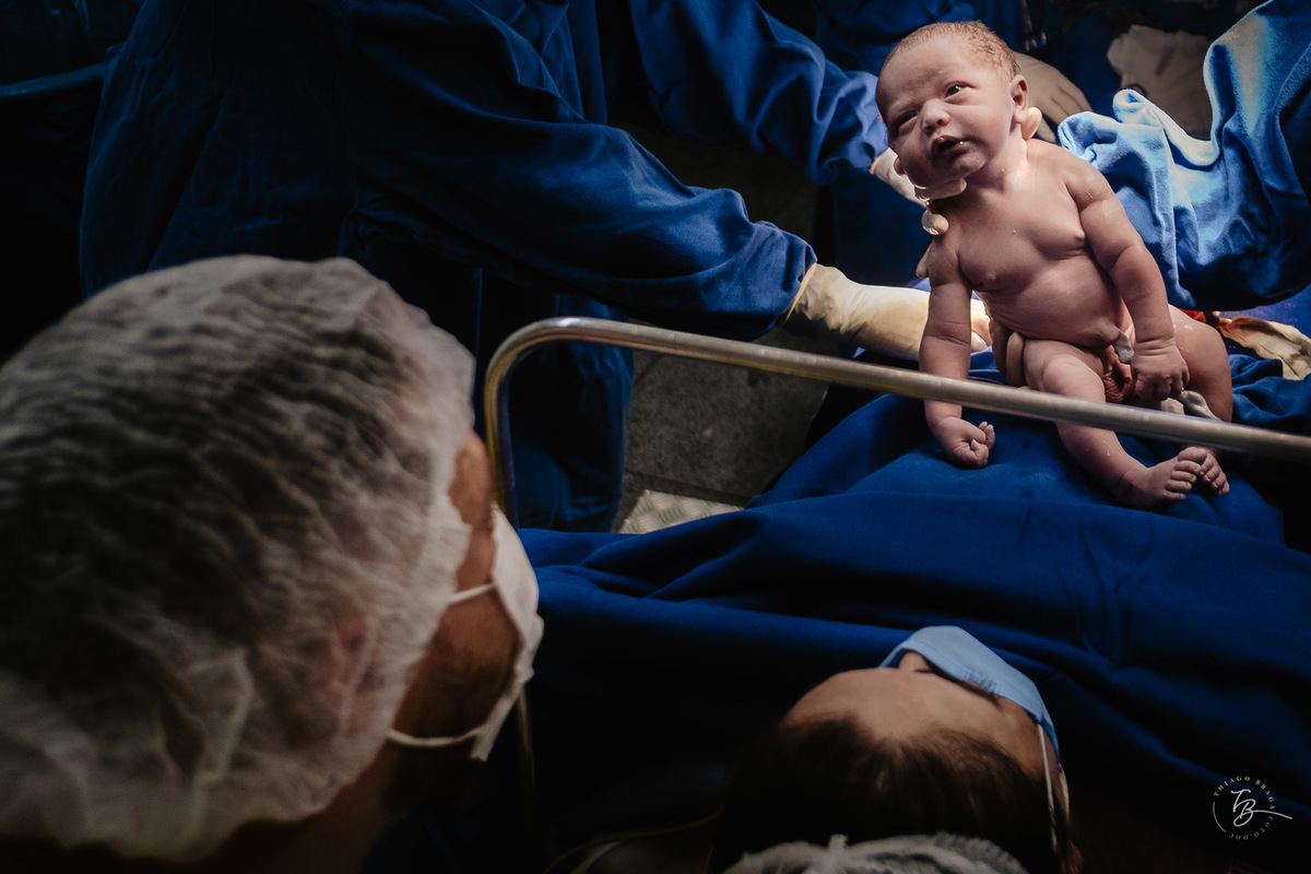 Visão do papai e mamãe na chegada do Heitor. Nascimento do Heitor. Parto Cesárea. Fotografia documental de parto por Thiago Braga.