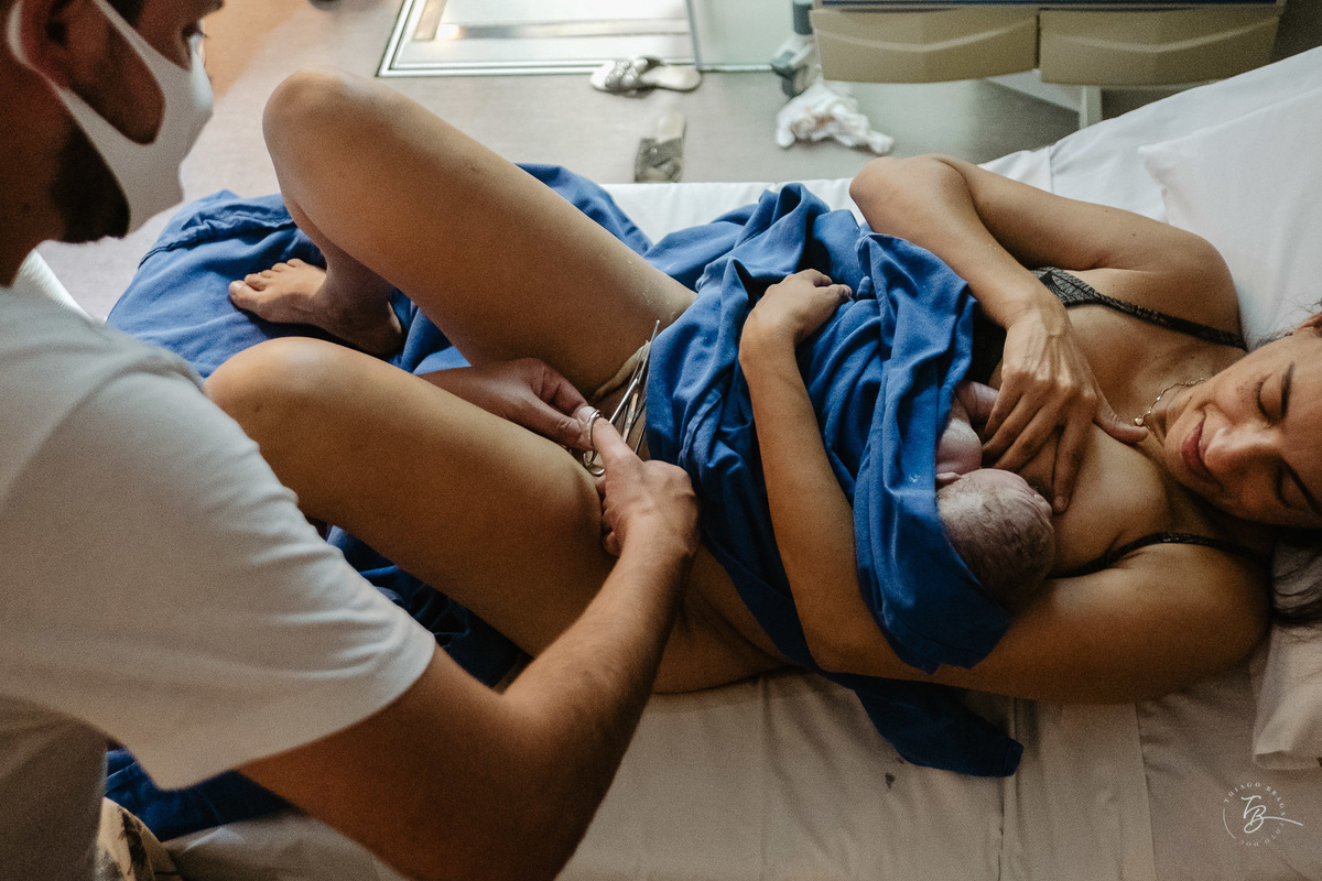 Cortando o cordão umbilical. Parto natural, nascimento do Nicolas por Thiago Braga fotografia. Maternidade Santa Helena em Florianópolis. Fotografia documental de parto. 
