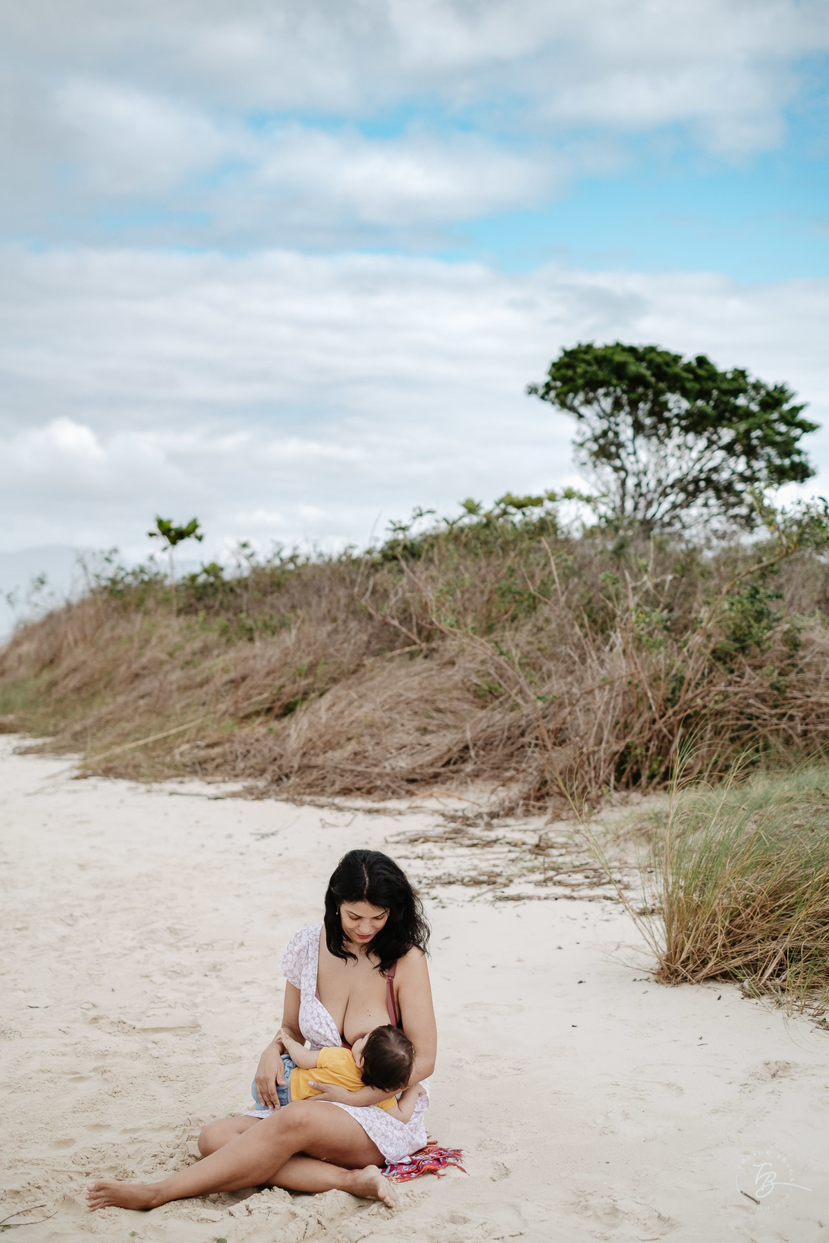 Hora de amamentar com paz e sossego em meio a natureza. Ensaio de família. Acompanhamento do primeiro aninho da Khloe. Praia da Daniela em Florianópolis/SC, por Thiago Braga Fotografia. 