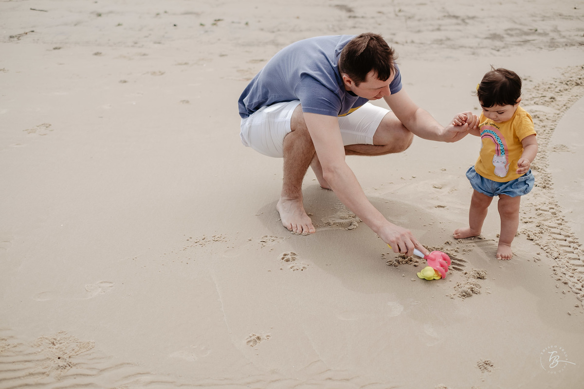 Brincando com o papai. Ensaio de família. Acompanhamento do primeiro aninho da Khloe. Praia da Daniela em Florianópolis/SC, por Thiago Braga Fotografia. 