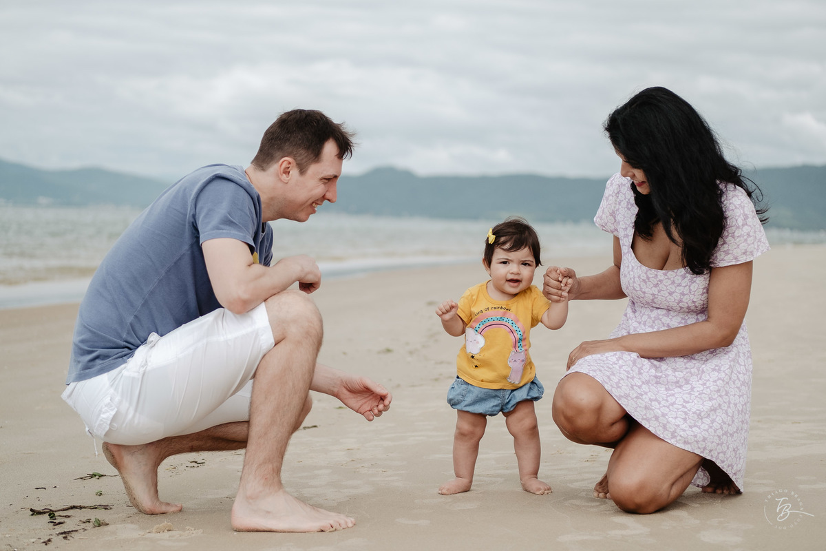 Todos juntinhos na areia. Ensaio de família. Acompanhamento do primeiro aninho da Khloe. Praia da Daniela em Florianópolis/SC, por Thiago Braga Fotografia. 