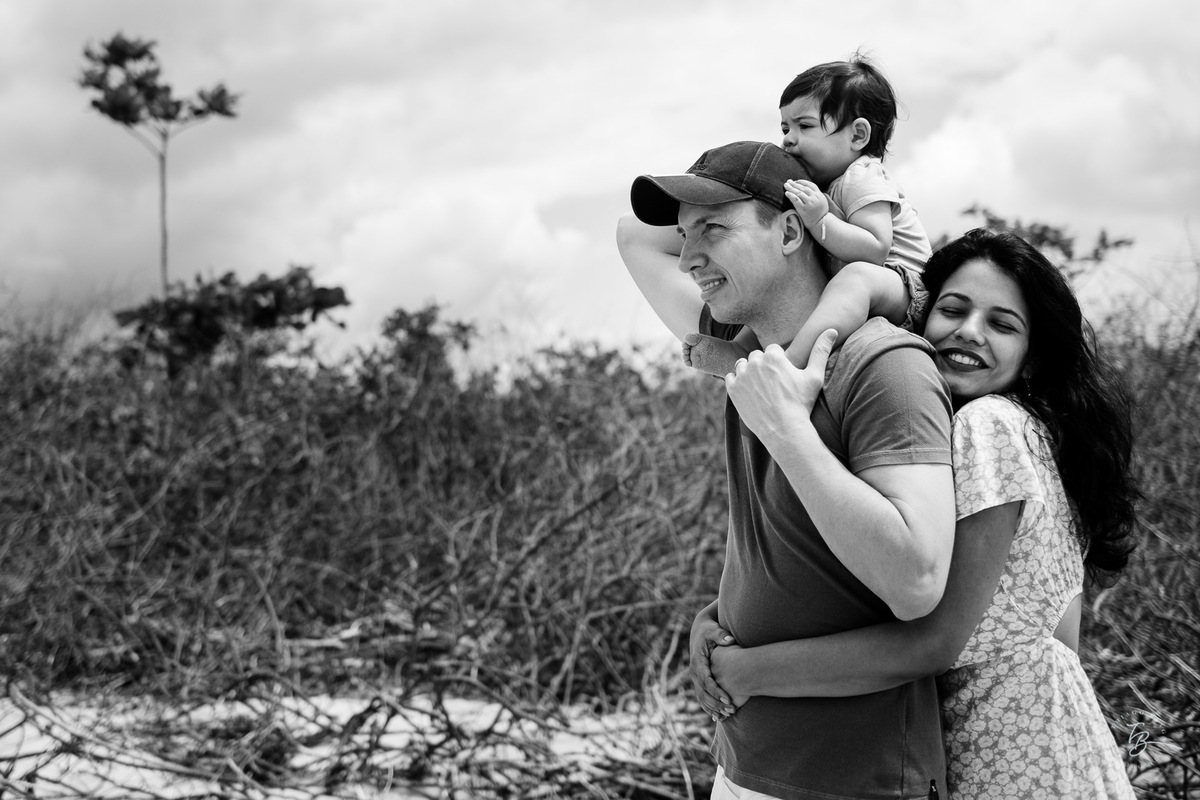 Abraçados na praia. Ensaio de família. Acompanhamento do primeiro aninho da Khloe. Praia da Daniela em Florianópolis/SC, por Thiago Braga Fotografia. 