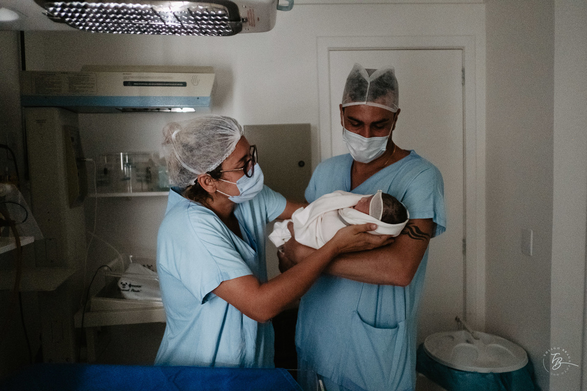 Papai pegando no colo pela primeira vez. Parto cesárea na maternidade Ilha, em Florianópolis, por Thiago Braga Fotografia.