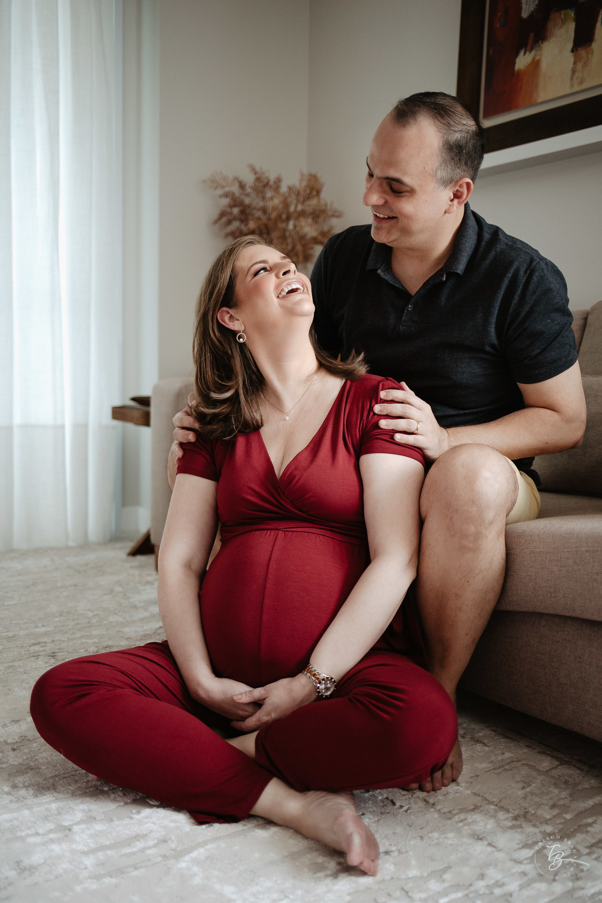 Casal rindo. Ensaio gestante em casa, na cidade de Itajai, por Thiago Braga fotografia